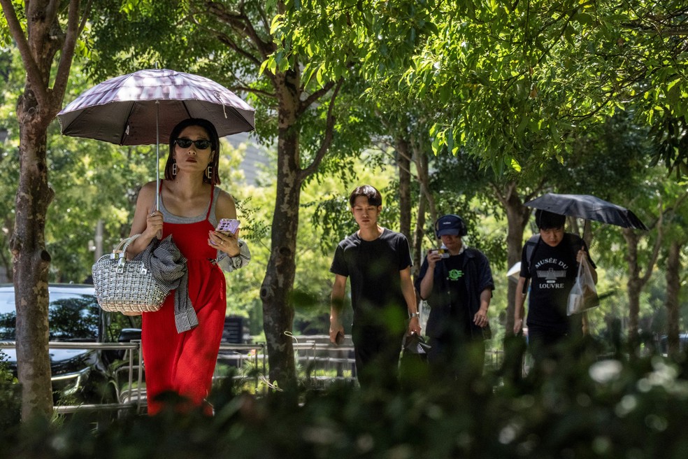 Pessoas caminham sob a sombra em um dia quente em Tóquio， em 27 de agosto de 2025 — Foto: Yuichi YAMAZAKI / AFP